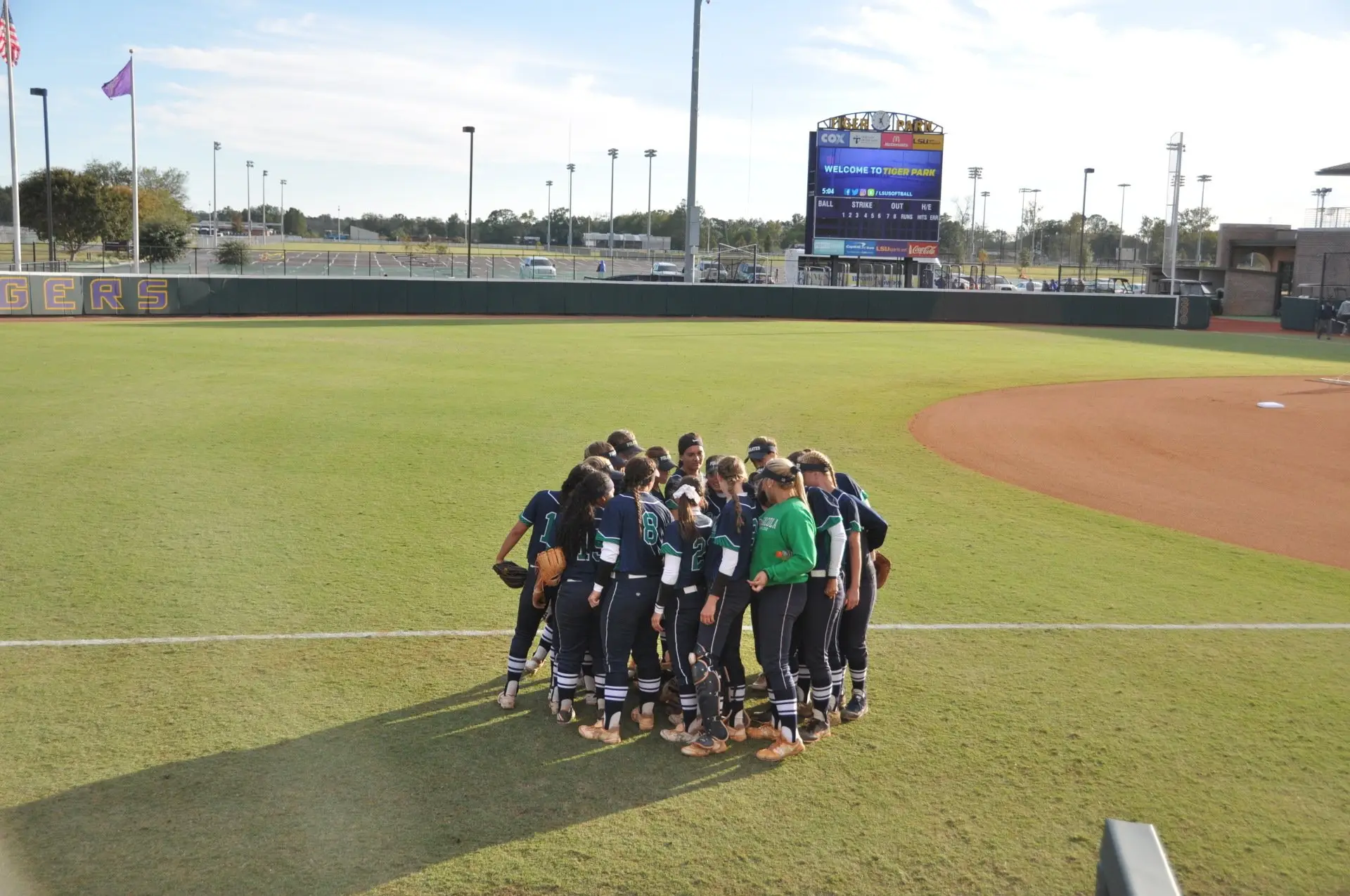 Pensacola State players in a team huddle in the outfield